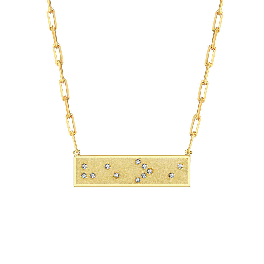 Gold necklace with a rectangular pendant featuring small crystals in Braille spelling He is Greater Than I on a white background