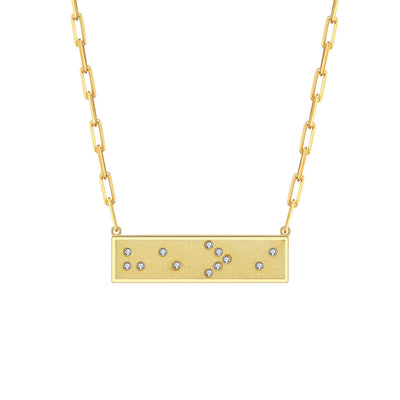 Gold necklace with a rectangular pendant featuring small crystals in Braille spelling He is Greater Than I on a white background