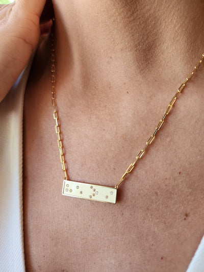 Gold Braille He > i necklace with a bar pendant on a person's neck