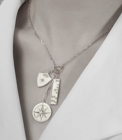 Three charms necklace on model in silver, model wearing compass and shield necklace