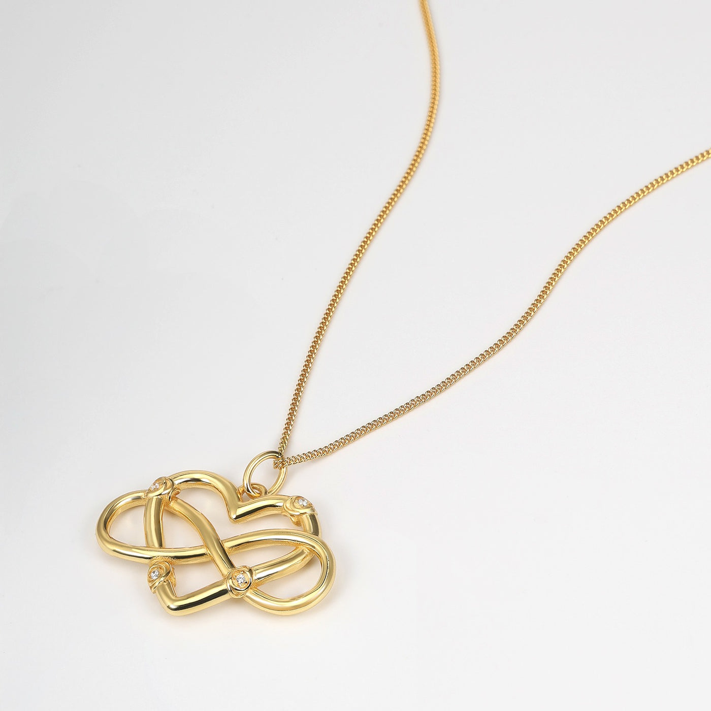 Gold necklace with a heart-shaped pendant on a light gray background